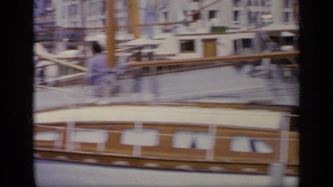 Moored wooden boat beside a quay with a person standing near the rail.