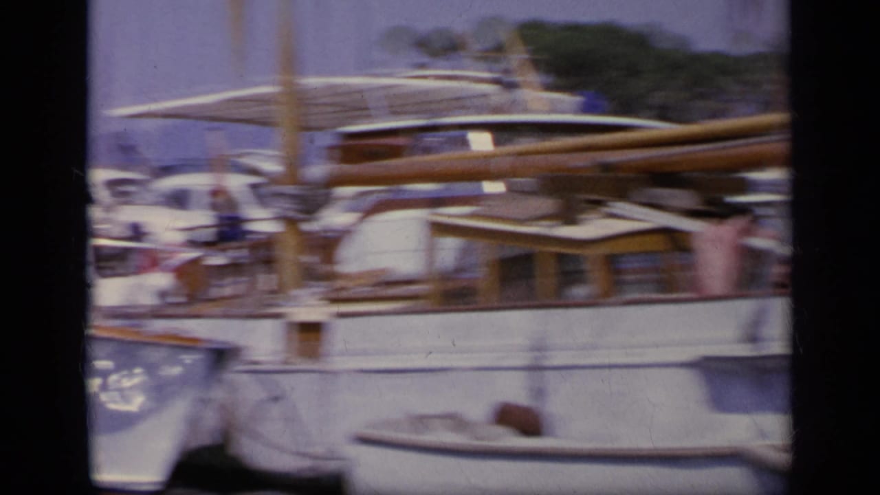 1963 Greece 8mm close view of a moored wooden boat, mast, railings, and soft-focus harbor background.