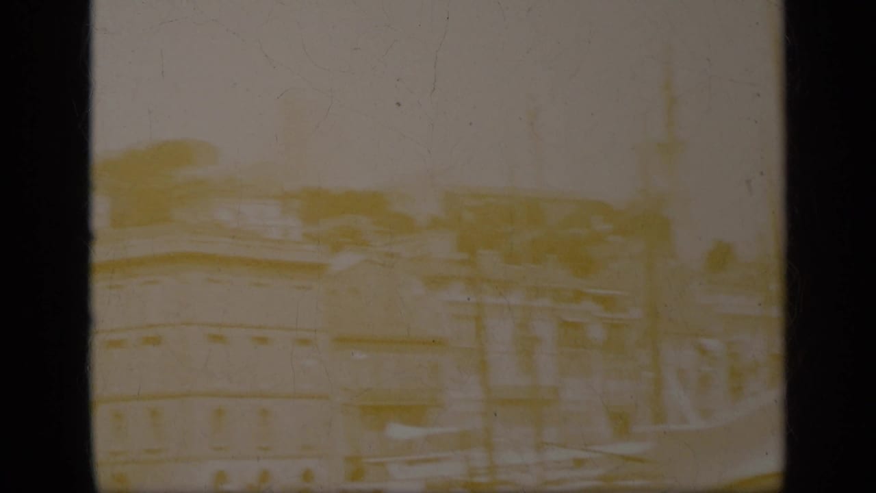 Faded view across rooftops and street structures with dark film borders.
