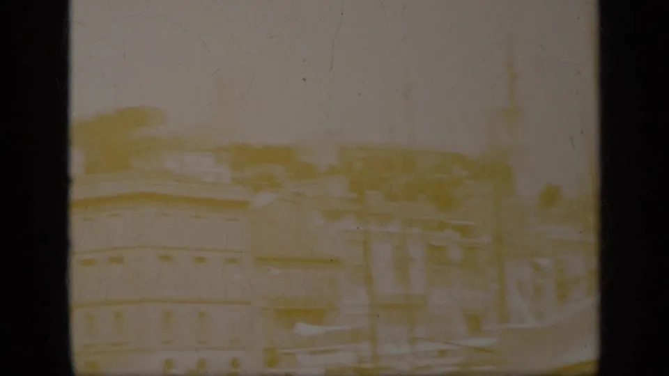 Faded 8mm frame from Greece, 1963, showing a soft urban view with rooftops, street structures, and heavy exposure loss.