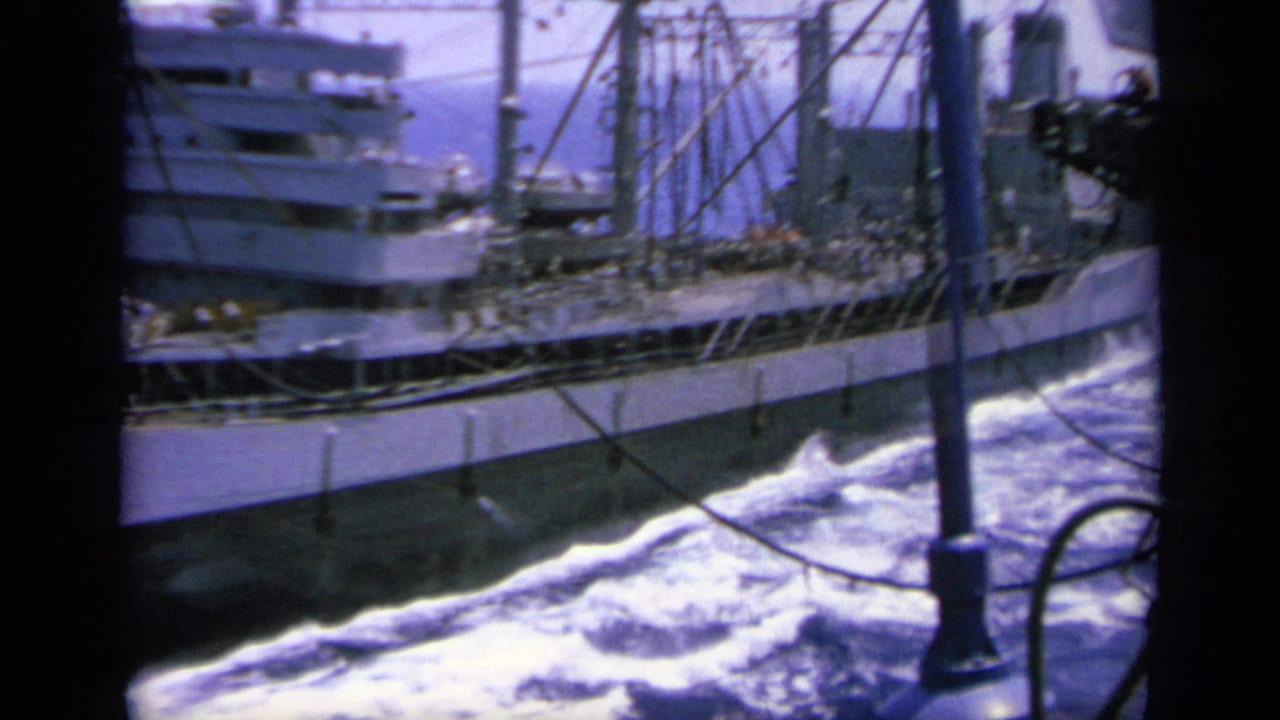 1963 Greece 8mm frame showing a gray ship with rigging alongside foaming wake near a naval vessel.