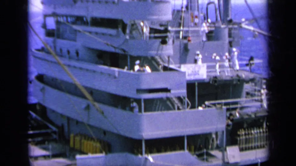 1963 Greece 8mm frame showing a naval ship at port with crew in white uniforms standing along the deck levels.