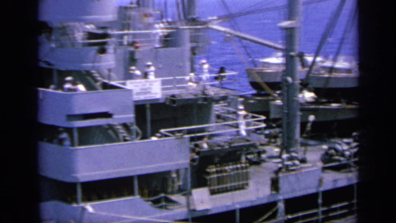 1963 Greece harbor view of a naval ship with crew on deck, rigging overhead and a smaller boat visible beside it.