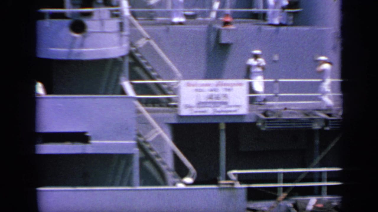 Sailors in white uniforms stand on a ship deck near railings and a replenishment sign.