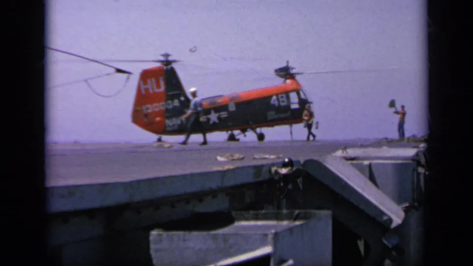 1963 Greece 8mm frame showing the Navy helicopter settled low on the ship deck as crew members move around the aircraft.