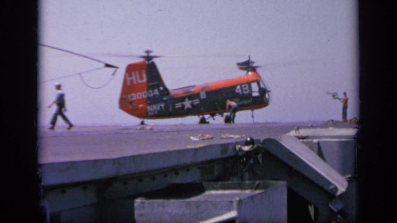 Navy HU-1 helicopter on a ship deck with crew members nearby.
