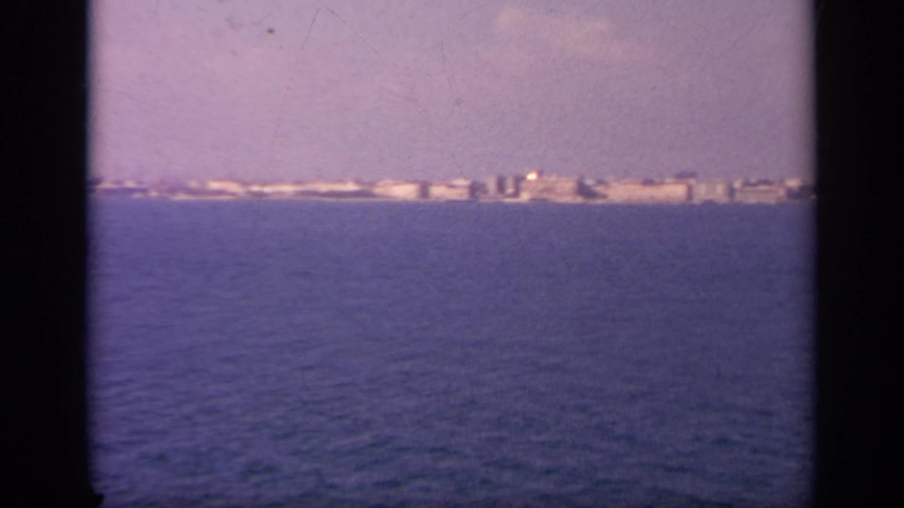 White coastal buildings stretch along the horizon beyond open water.