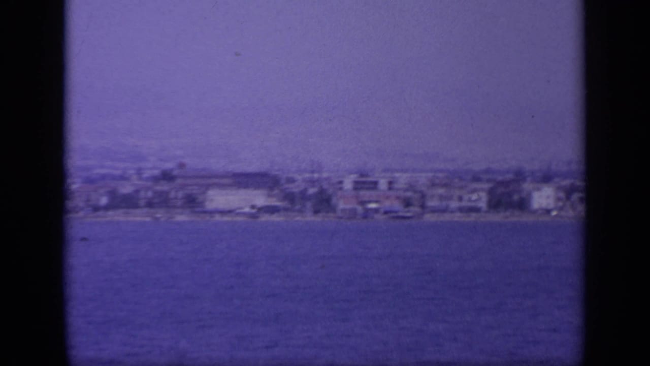 Waterfront buildings on a distant shore with a dark vertical band near center.