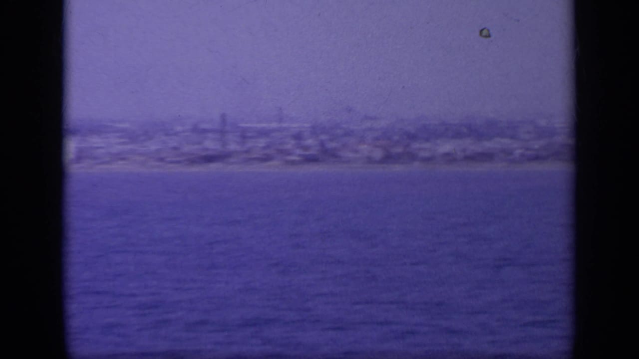 Greek coastal skyline seen from across the water in a soft, blue-purple 8mm frame from 1963.
