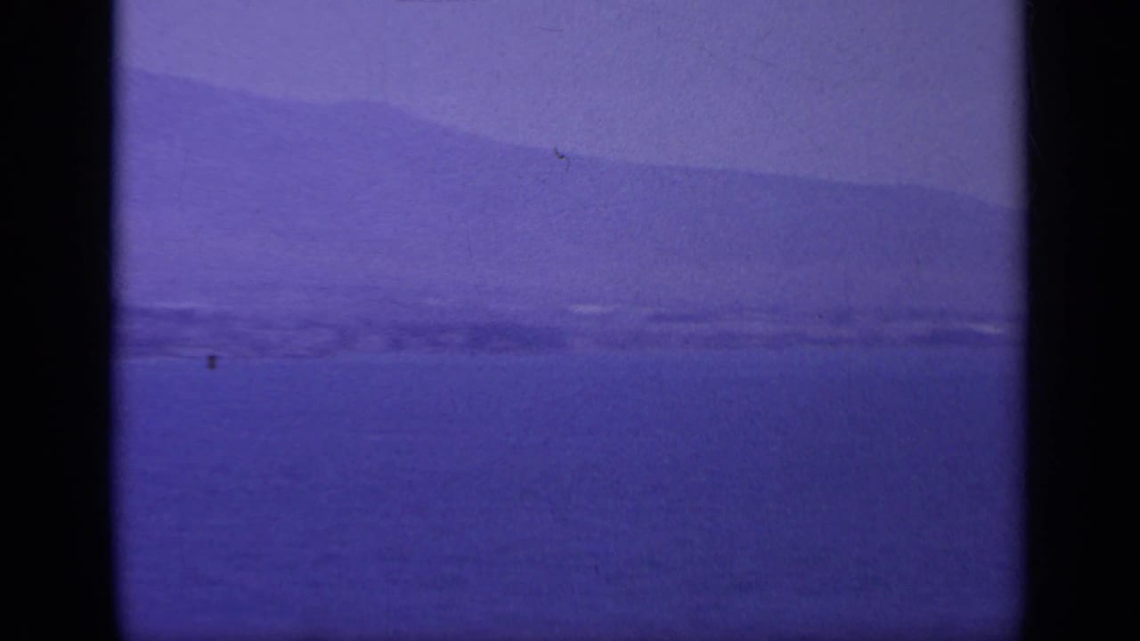 1963 Greece home-movie view of open sea, a faint distant coast, and broad mountains softened by haze and film aging.