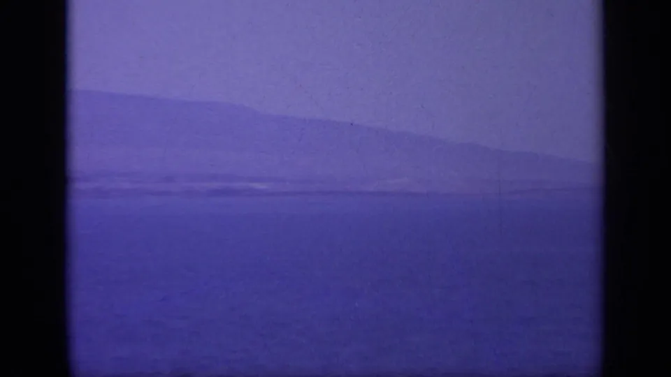 1963 Greece 8mm frame showing hazy open water and a faint distant landmass under a purple color cast.