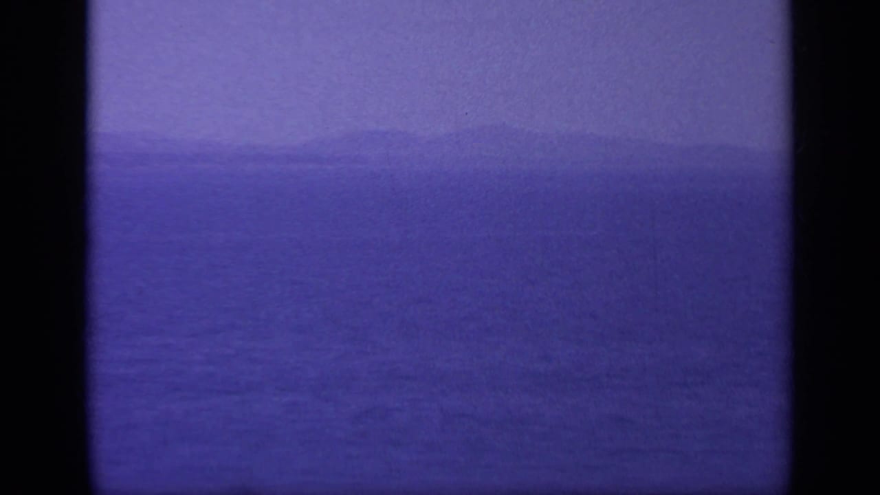 Hazy seascape with open water and distant land near the horizon.