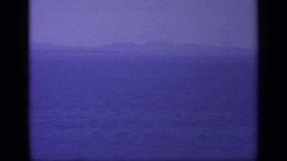 1963 Greece 8mm frame with calm water, a low horizon, and distant land softened by haze and film grain.