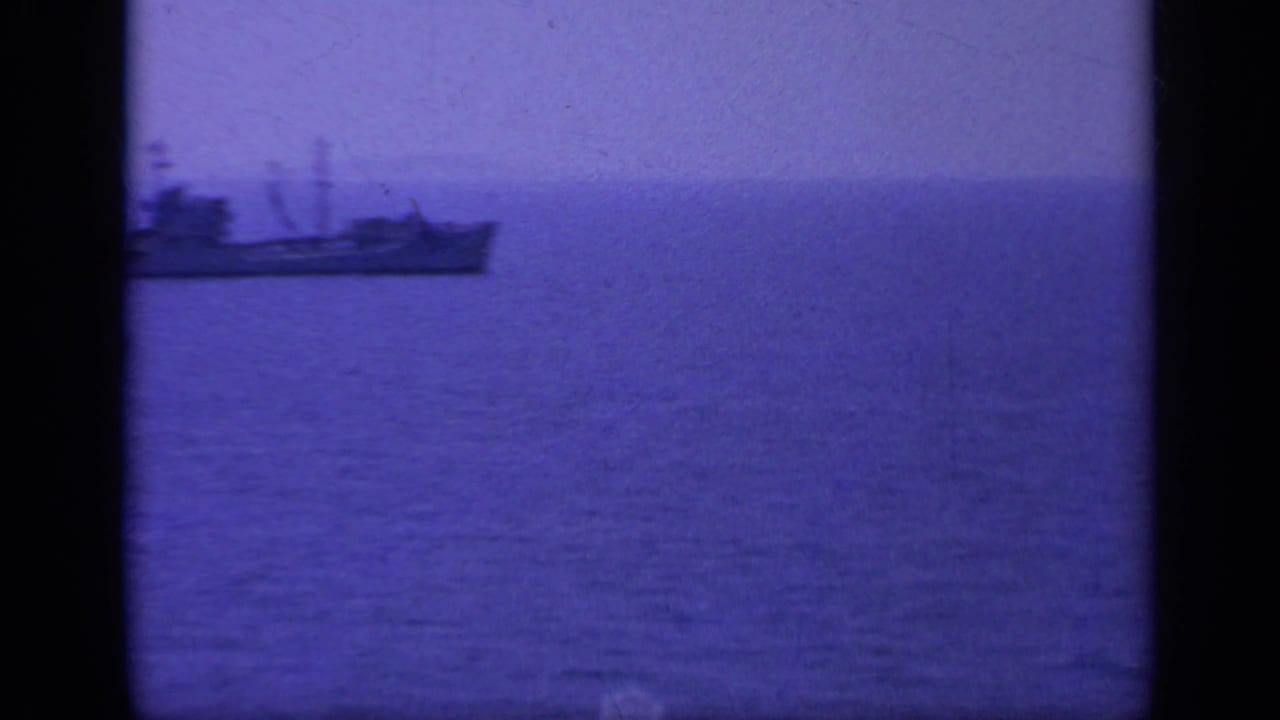 1963 Greece 8mm frame with a distant ship on calm water, bordered by dark film-frame edges and a purple cast.