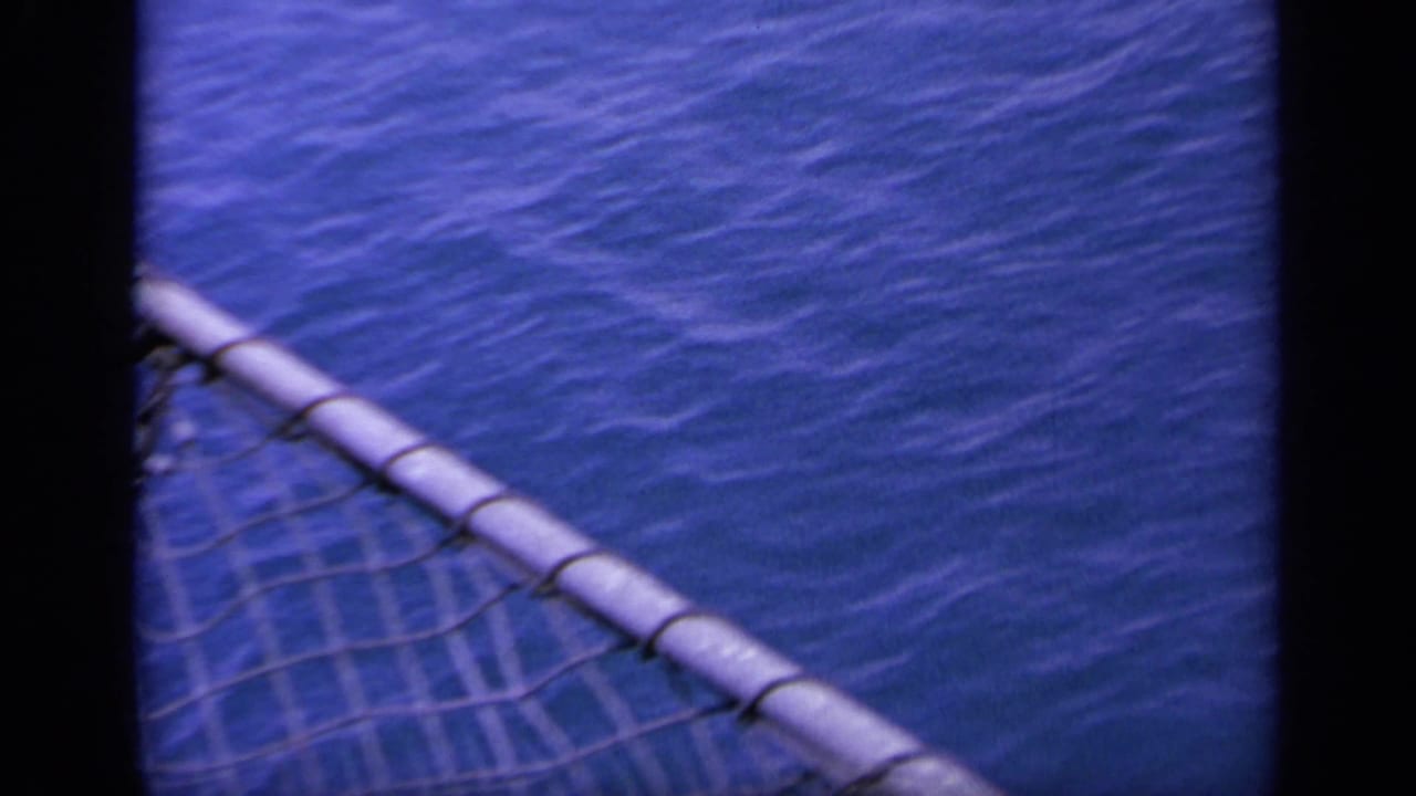 Ship rail and rope netting cross the foreground above open blue water in the 1963 Greece maritime footage.