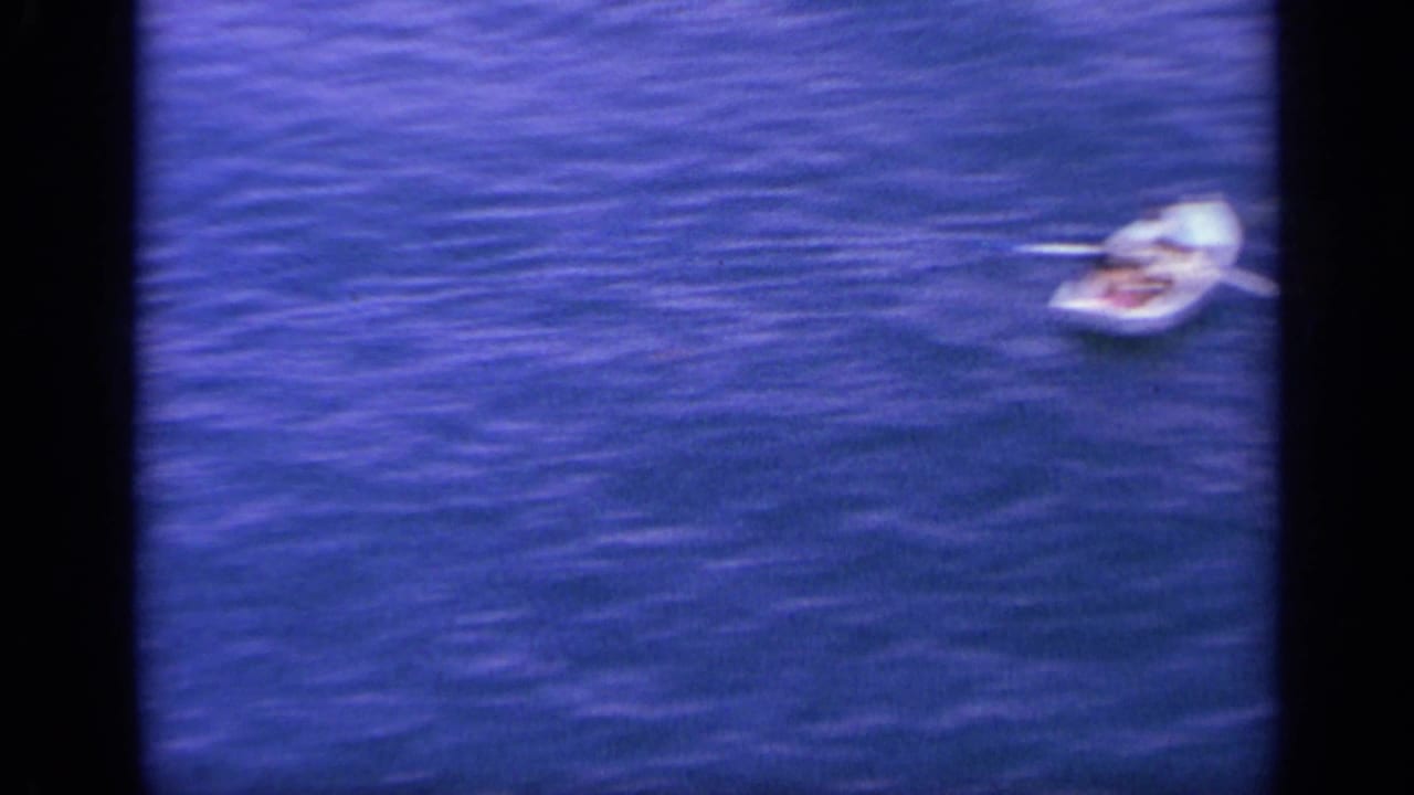 A small white boat sits on the blue water near Greece in this short 1963 home-movie maritime view.