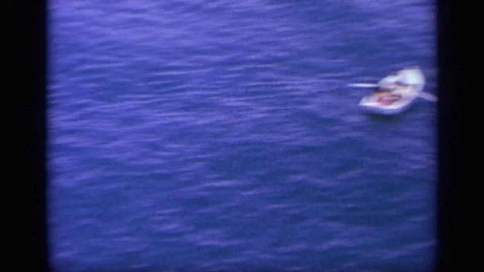 A small white boat sits on the blue water near Greece in this short 1963 home-movie maritime view.