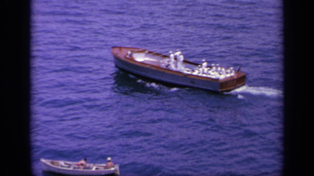 1963 Greece frame showing a wooden motorboat with uniformed men, with a small rowboat lower in the scene.