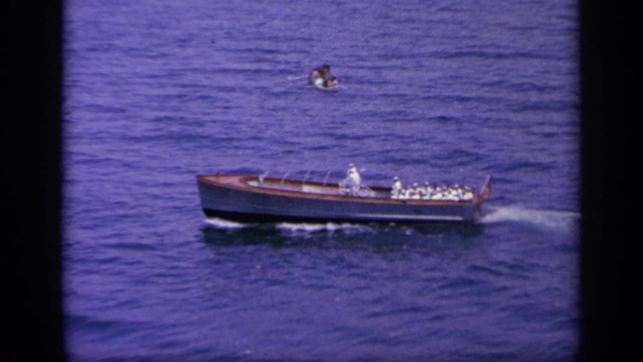 1963 Greece frame of the wooden motorboat traveling across open water, seen from an elevated home-movie angle.