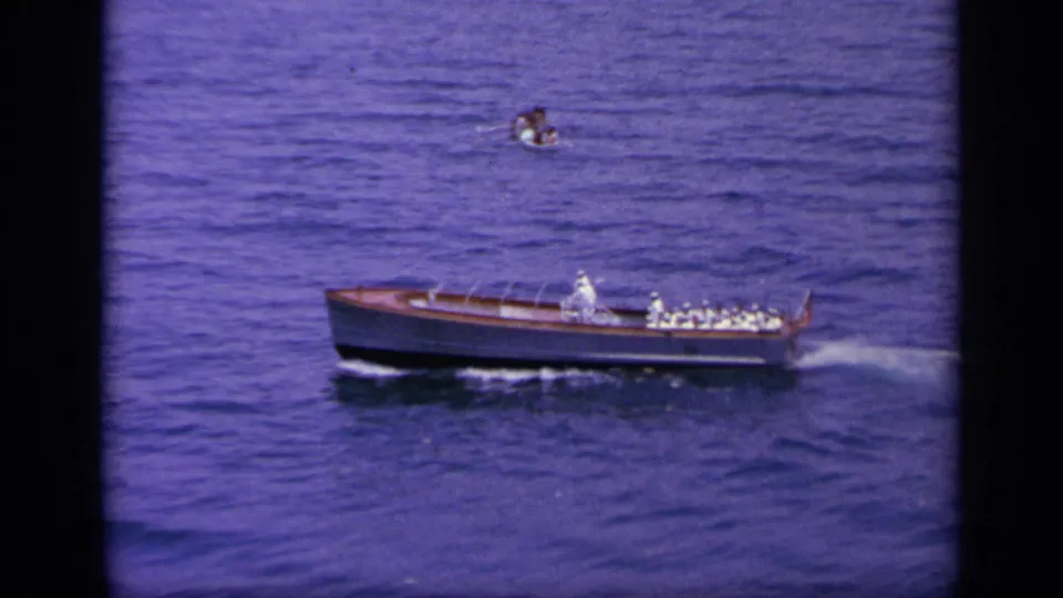 1963 Greece frame of the wooden motorboat traveling across open water, seen from an elevated home-movie angle.