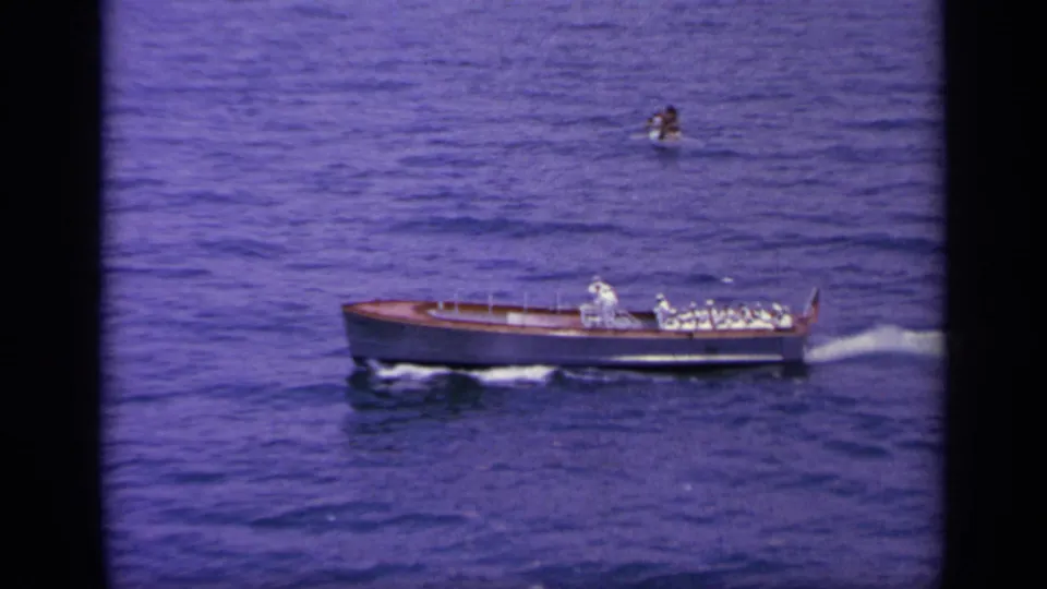 1963 Greece 8mm frame showing a small naval boat with uniformed personnel crossing deep blue water.