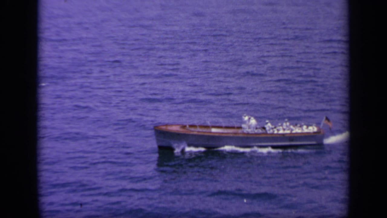 Small naval craft in 1963 Greece footage travels across open water, carrying uniformed figures and leaving a white wake.