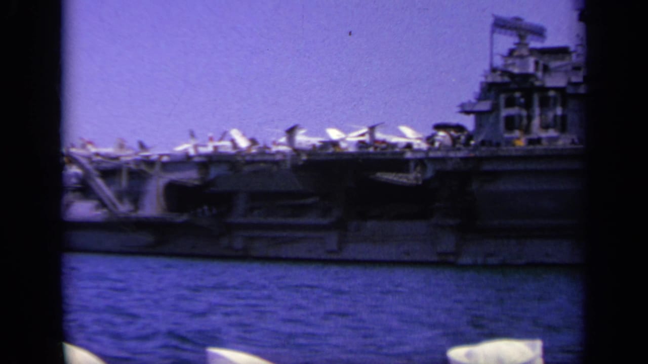 Side view of a carrier with aircraft on deck and superstructure at right.