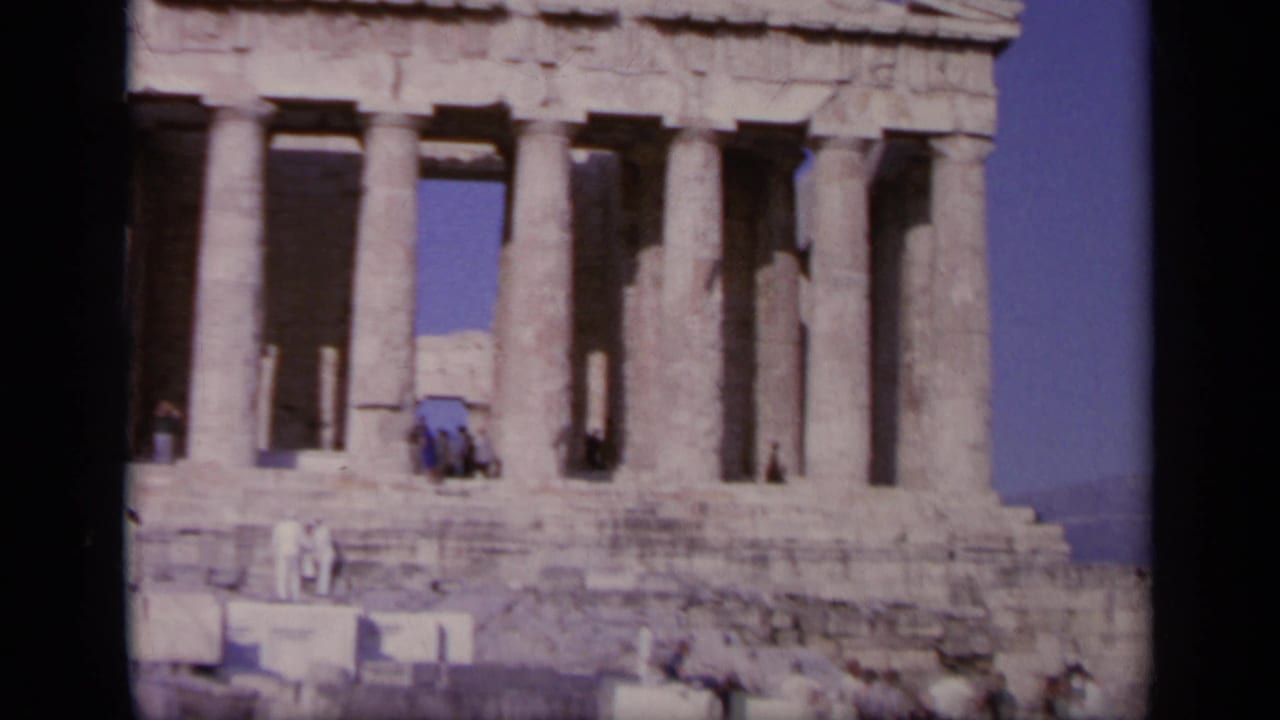 Front view of the Parthenon with tourists on the steps and columns behind them.