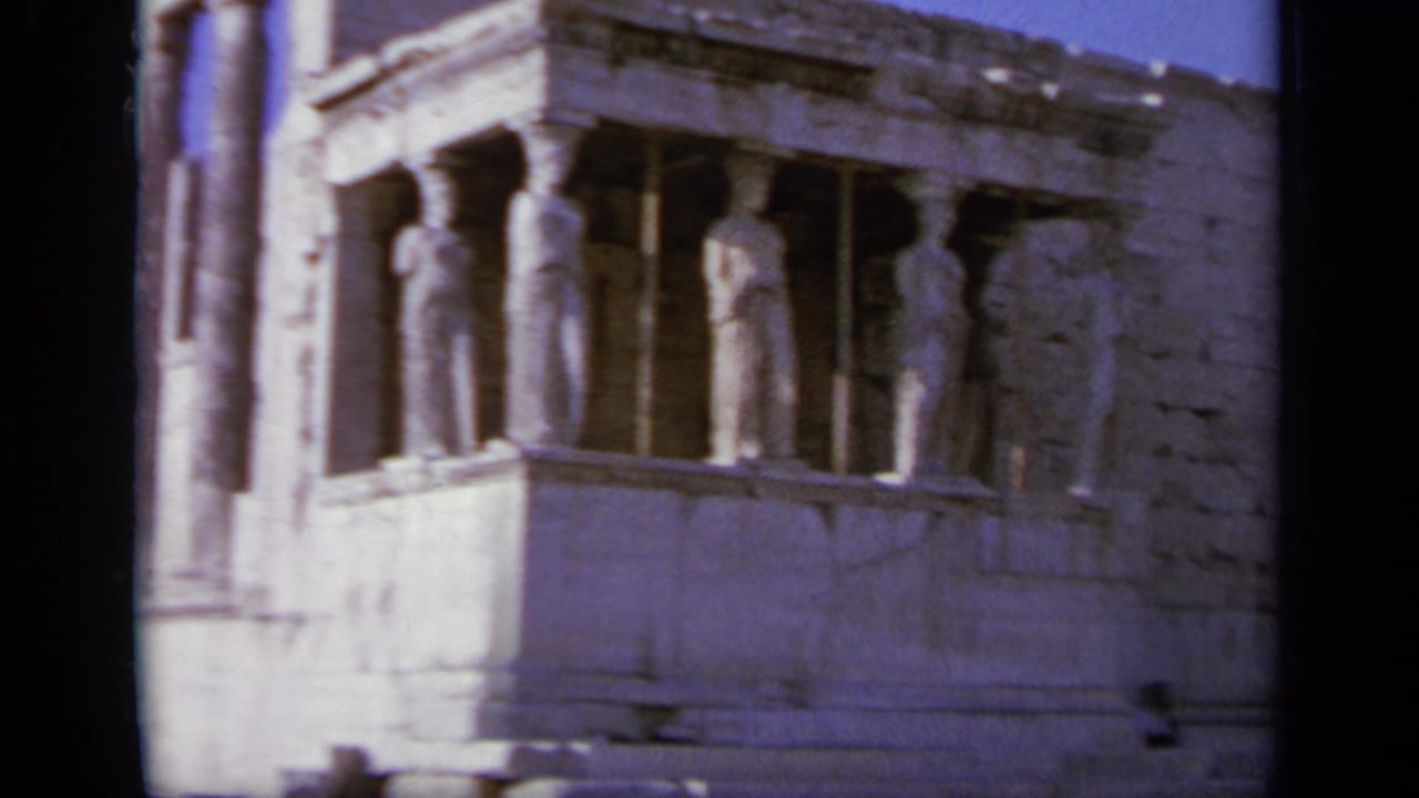 Closer view of caryatid figures supporting a stone porch on an ancient building.