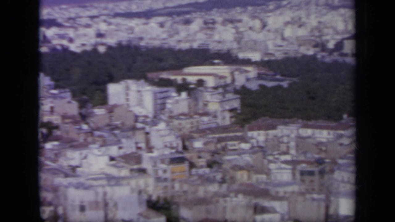 1963 Greece frame showing a high city view with a wooded area, oval stadium-like landmark, and surrounding buildings.