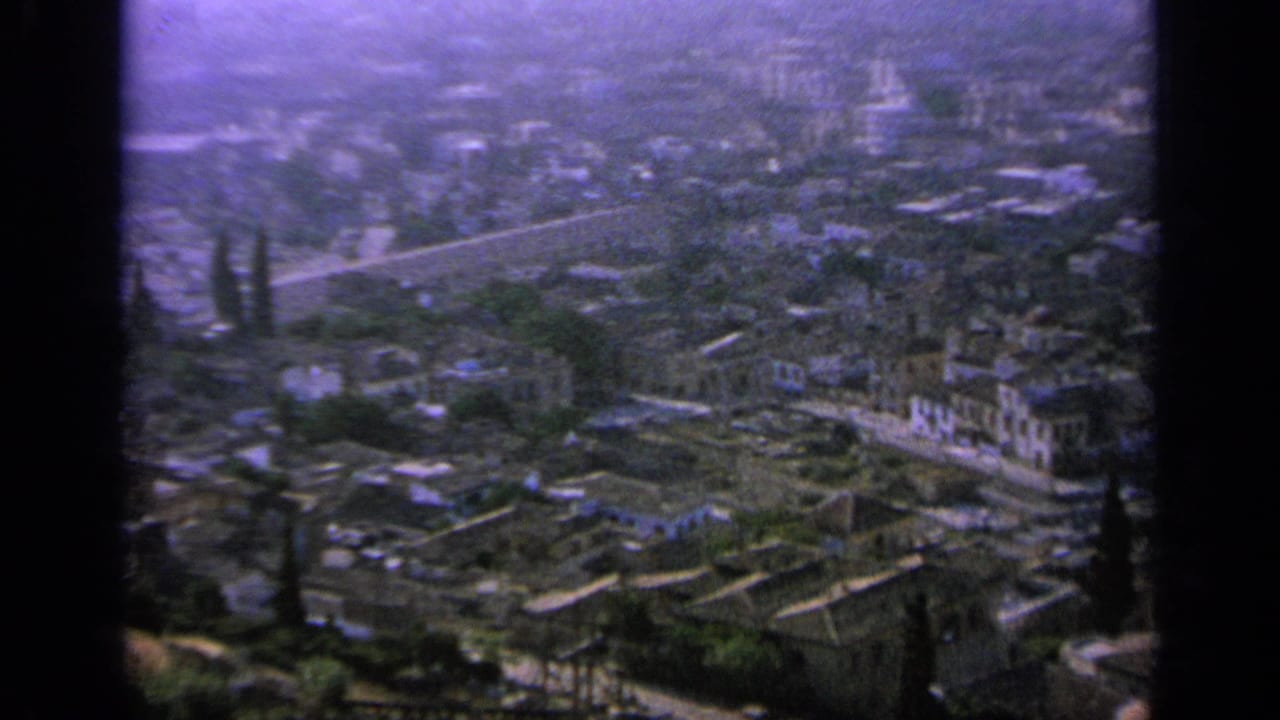 1963 Greece 8mm view where dense buildings give way to greener park-like areas, roads, and trees.