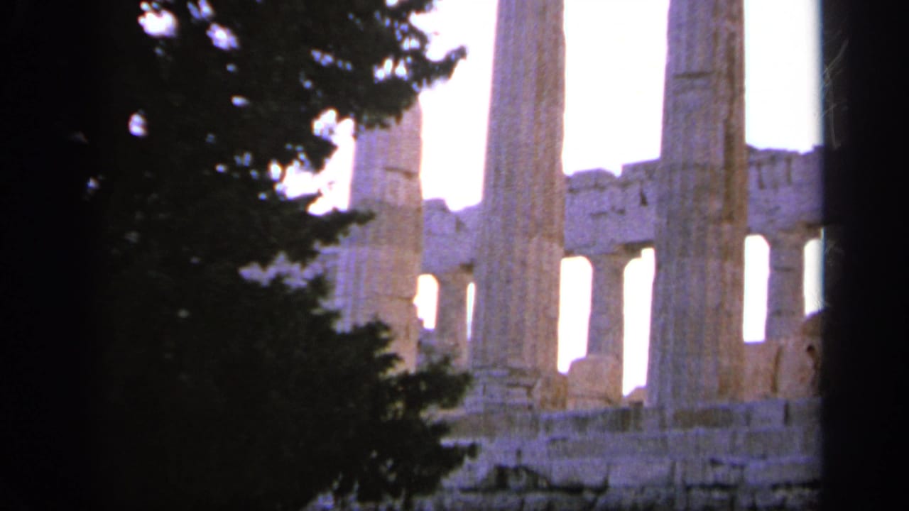 1963 Greece travel frame showing pale ancient stone columns and temple structure partly blocked by a dark tree silhouette.