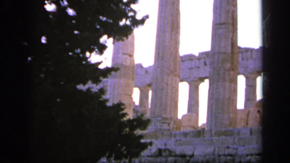 1963 Greece travel frame showing pale ancient stone columns and temple structure partly blocked by a dark tree silhouette.