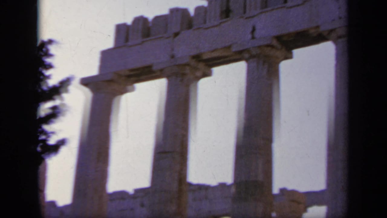 1963 8mm Greece frame with classical stone columns, upper temple masonry, and bright overexposed sky.