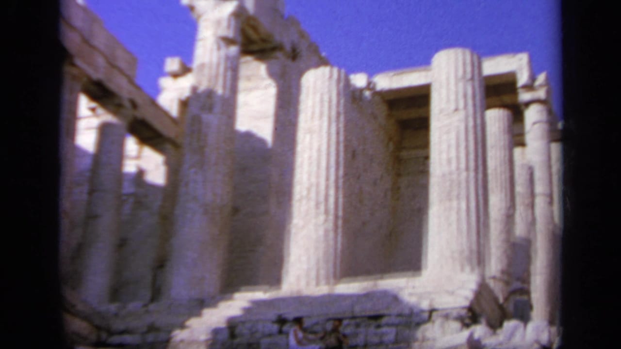 Ancient stone columns and partial ruins under a bright blue sky.