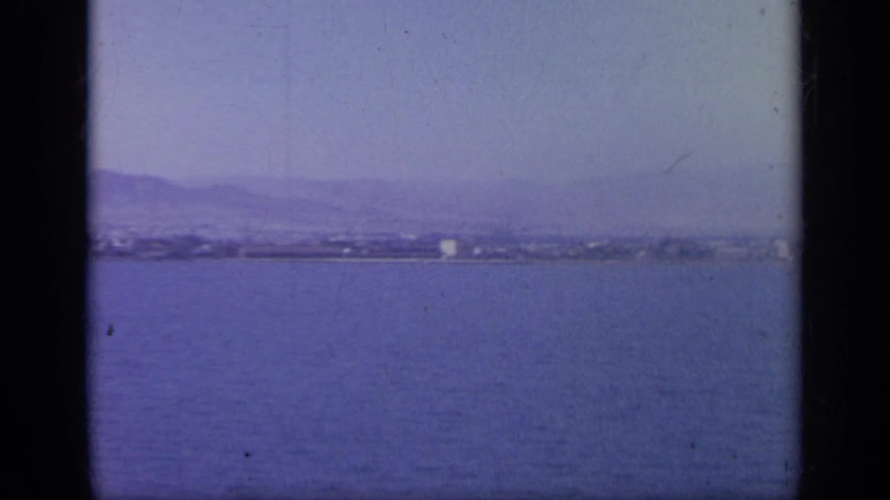 Wide water view with distant shoreline and mountains under a hazy sky.