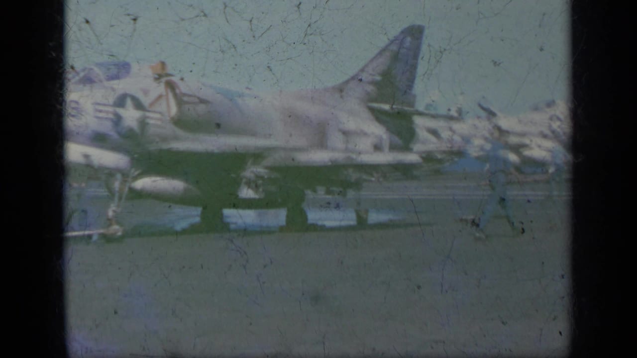U.S. Navy jet parked on a carrier deck with star insignia and support equipment nearby.