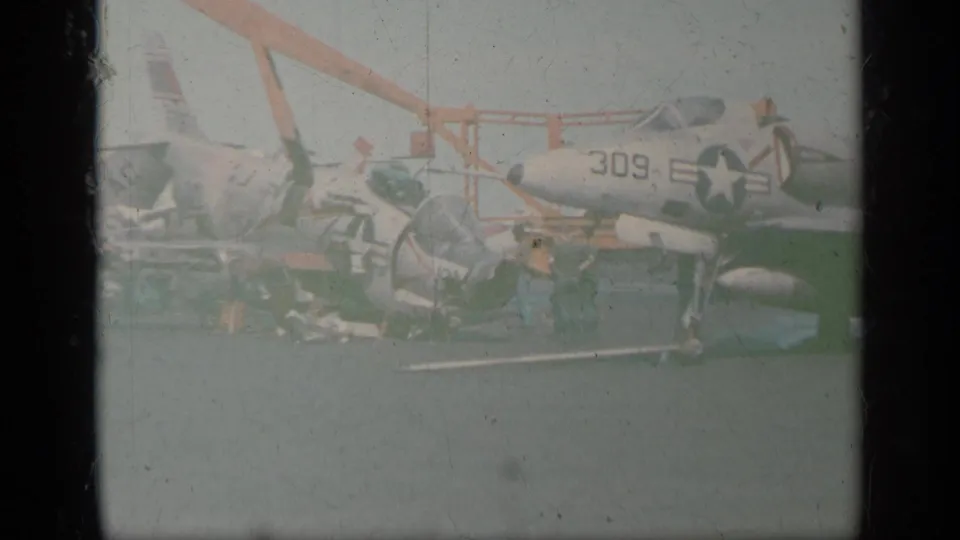 Faded color 8mm frame shows the side of a U.S. Navy jet marked 309 on a carrier deck in the Greece 1963 footage.