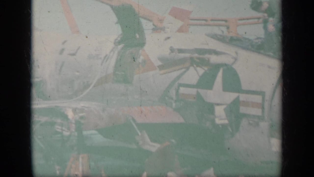 Faded view of a white military jet with U.S. star marking and deck equipment.