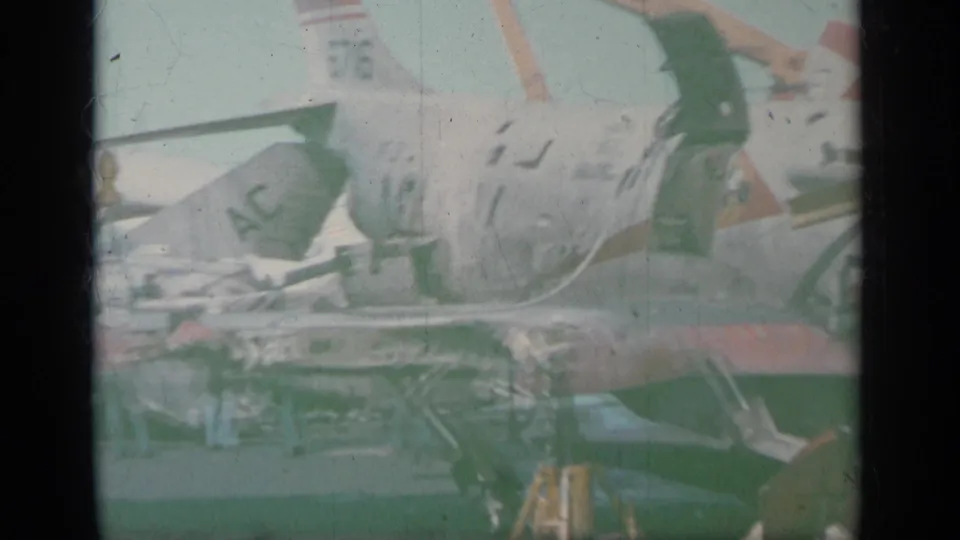 1963 Greece 8mm view of a parked white military jet, with tail and fuselage details softened by faded color and exposure.