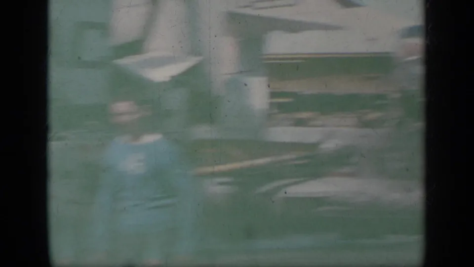 Soft 8mm frame from Greece in 1963 showing a blurred figure near U.S. Navy jet aircraft on a carrier deck.