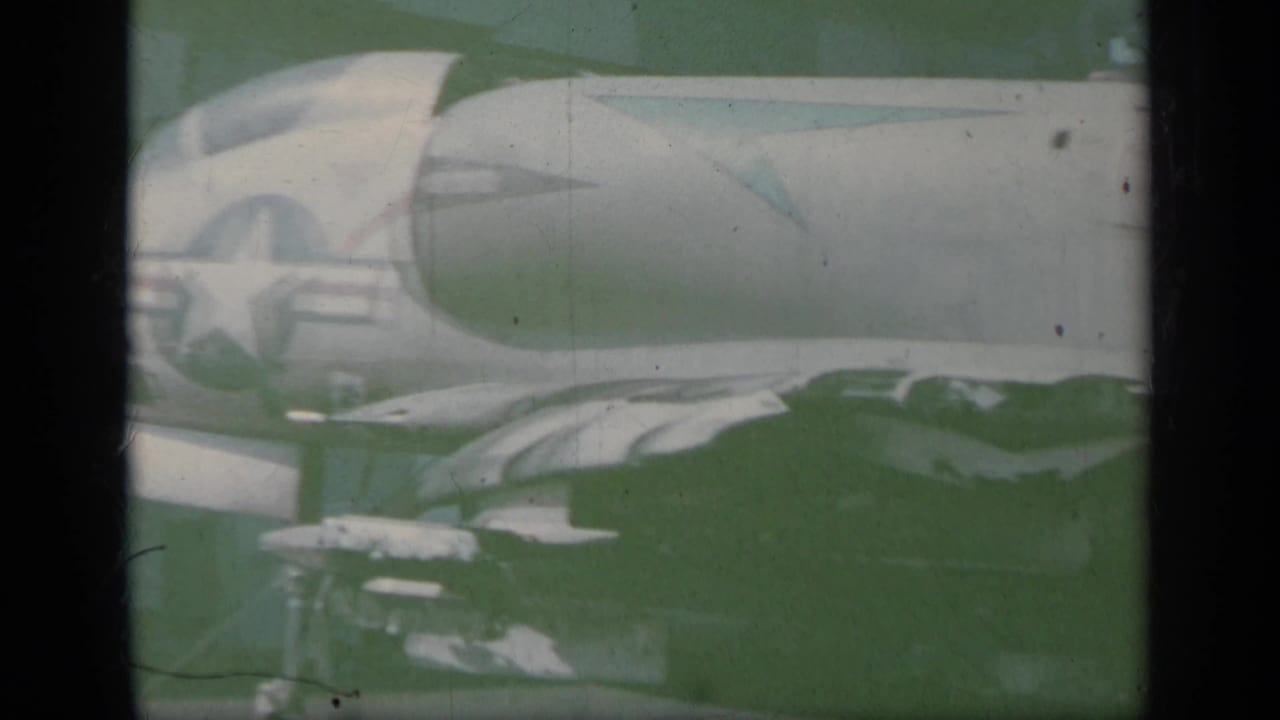 Scorched jet fighter fuselage on a carrier deck with a U.S. star marking visible.