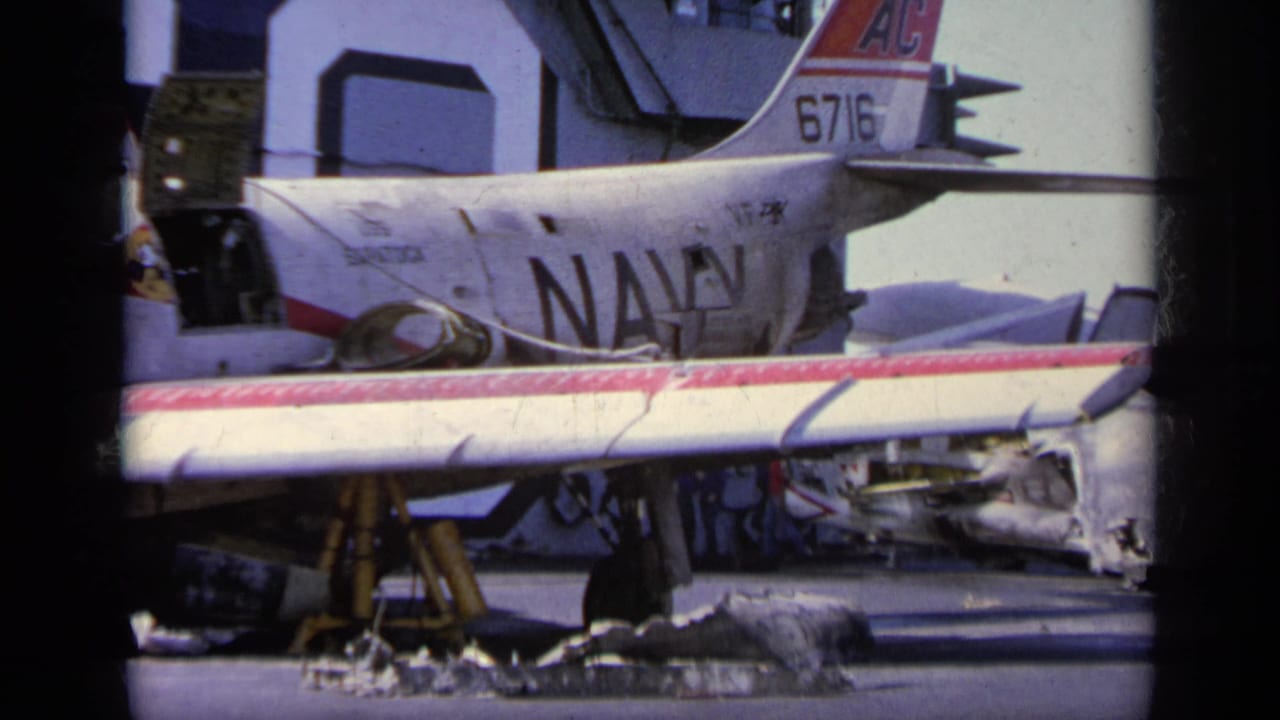 Damaged Navy aircraft on a tarmac with tail number 6716 and debris nearby.