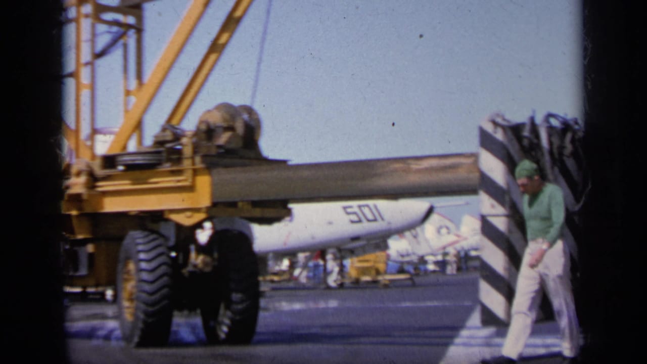 Yellow aircraft handling machine beside a white jet marked 501 as a man walks across the airfield.