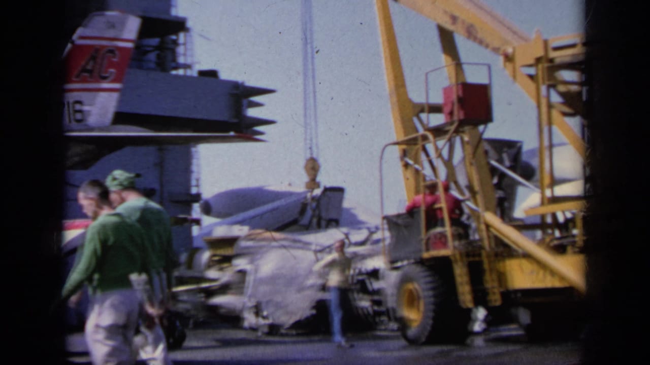 1963 Greece 8mm frame showing crew near a wrecked military aircraft section being handled by a crane on a ship deck.