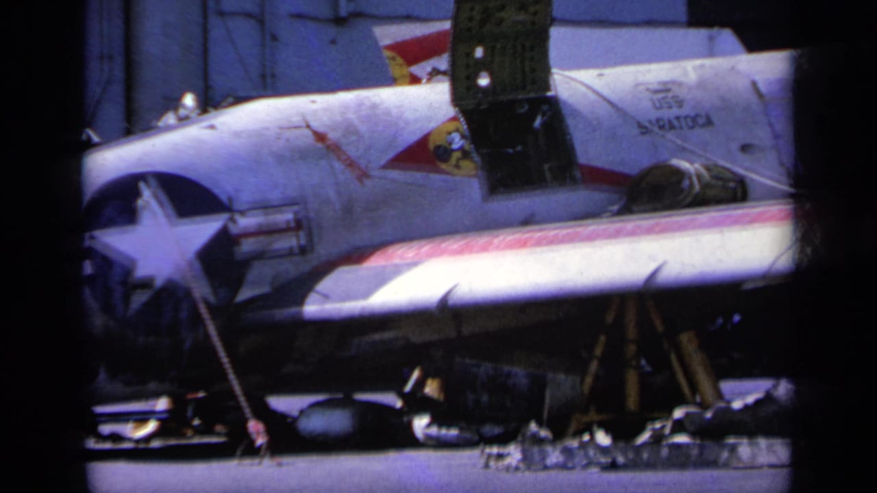 1963 Greece 8mm frame showing a U.S.-marked military aircraft on an airfield with support equipment nearby.