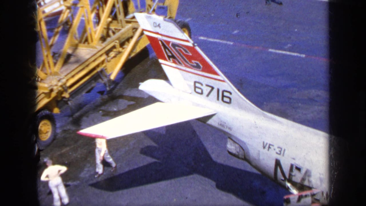1963 Greece 8mm frame showing an F-104 Starfighter tail marked 6716 beside ground equipment and personnel on the tarmac.