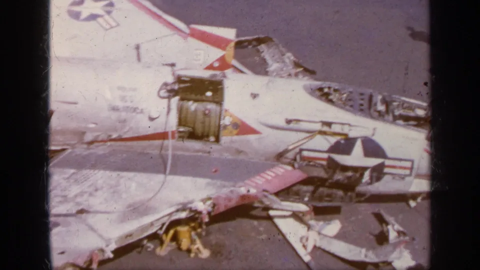 1963 Greece 8mm frame showing the damaged F-104 wing area, open service panels, aircraft insignia, and a person on the tarmac.