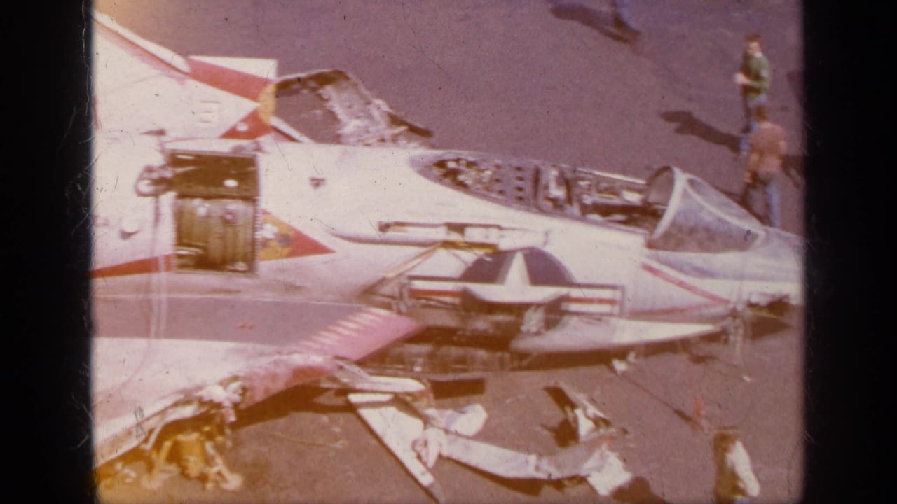 1963 Greece 8mm frame showing a U.S. Air Force jet with open cockpit, exposed aircraft section, and ground crew on the tarmac.