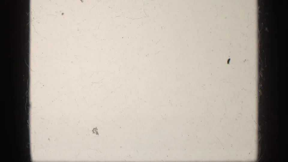 Mostly blank 8mm frame from the 1963 Greece reel, showing pale exposure, film dust, scratches, and dark gate borders.